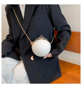 Elegant white lace pearl sphere bag with golden chain strap on a black blazer