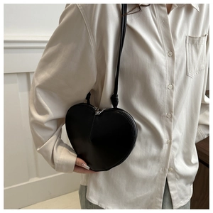 Détail d'un sac à bandoulière noir en forme de cœur avec texture mate et fermeture éclair