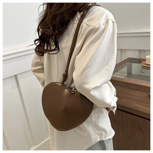 Détail d'un sac bandoulière cœur marron foncé en cuir lisse avec fermeture éclair en métal