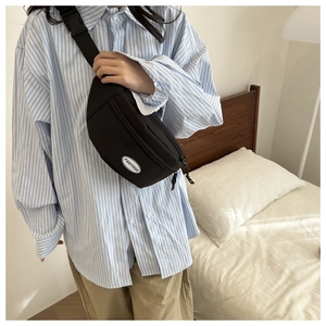 Dettaglio di un borsello nero in tessuto Oxford indossato a tracolla in stile casual