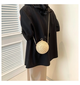 Detail of spherical woven evening bag with golden chain strap and round metal clasp