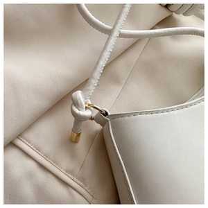 Detail of the white leather shoulder bag featuring unique knotted straps and gold hardware