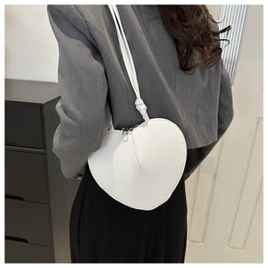 Sac bandoulière blanc en forme de cœur avec détail de bandoulière nouée sur un mannequin