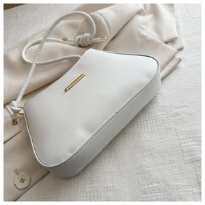 Close-up of minimalist white shoulder bag with gold hardware on a beige blazer