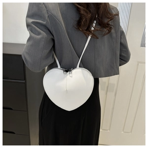 Vue détaillée d'un sac bandoulière blanc en cuir en forme de cœur sur un modèle