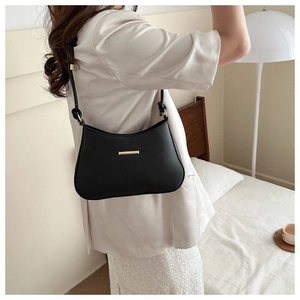 Detail of a chic black leather underarm bag with elegant gold buckle shown from side