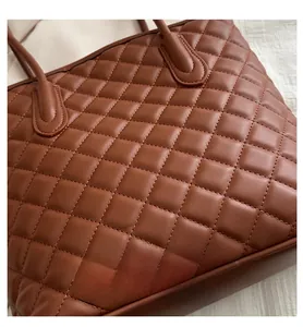Macro shot of deep brown quilted faux leather texture on a spacious tote bag