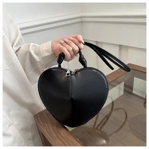 Vue détaillée du sac à main noir en forme de cœur avec zips argentés et poignée nouée