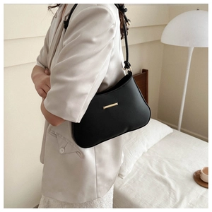 Detail of black underarm bag with gold metal buckle and leather strap on shoulder
