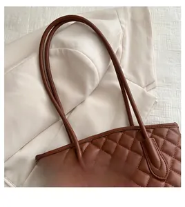 Detail of brown quilted tote bag with classic diamond stitching and slim handle straps