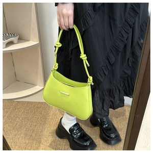 Detail view of bright green crescent underarm bag with unique knotted strap and gold hardware