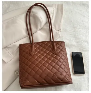 Brown quilted tote bag shown with a smartphone to demonstrate large capacity size