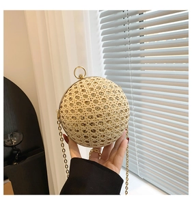 Close-up of golden spherical evening bag with hollow-out glitter design and chain strap
