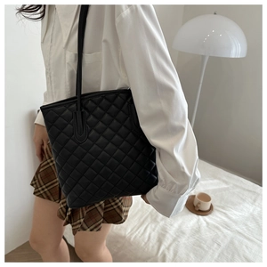 Detail of classic black quilted tote bag featuring elegant diamond lattice stitching design