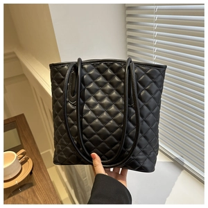 Macro detail of black quilted leather tote bag featuring elegant diamond lattice stitching
