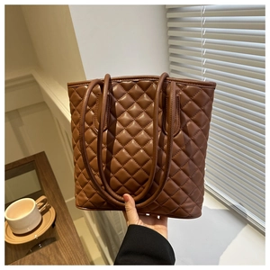 Detail of dark brown quilted leather tote bag showing diamond stitching and slim straps