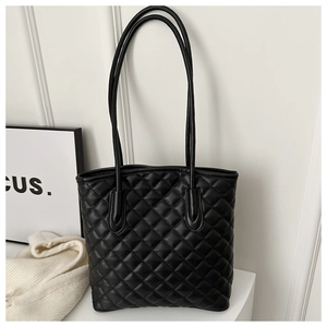 Detail of classic diamond quilted texture and long shoulder straps on a black tote bag