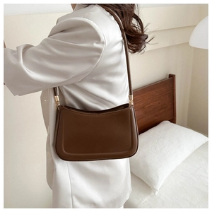 Sac sous le bras baguette vintage marron en cuir lisse porté par un mannequin dans une chambre
