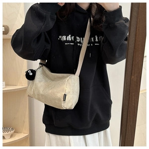 Detail of beige corduroy crossbody tote bag featuring a cute soot sprite plush pendant