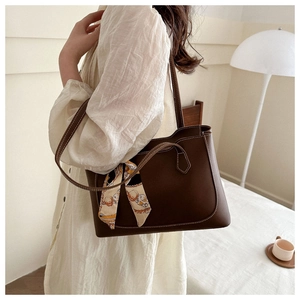 Brown leather tote bag with contrast stitching and decorative scarf detail on handle