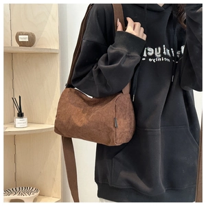 Detailed texture of brown corduroy cylindrical crossbody bag with adjustable wide strap