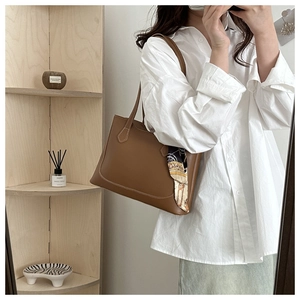 Detail of a brown leather tote bag with silk scarf and fine contrast stitching detail