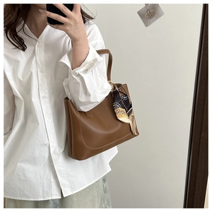 Detail of dark brown leather tote bag with vintage print silk scarf and white stitching