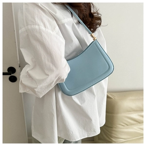 Close-up of light blue baguette bag with smooth texture and golden metal hardware details
