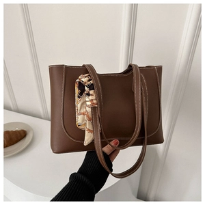 Brown tote bag with white stitching detail and a decorative silk scarf on the handle