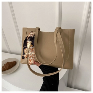 Close-up of khaki tote bag with textured leather and decorative patterned silk scarf