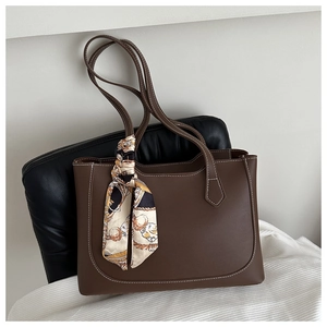 Detail of dark brown leather tote bag with white stitching and decorative silk scarf