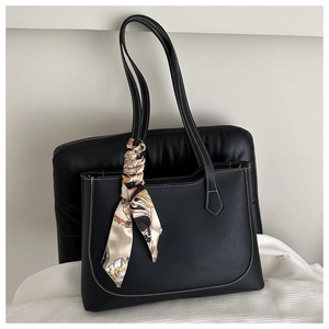 Detail of black tote bag with white stitching and decorative silk scarf on handle