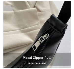 Close-up of premium silver metal zipper pull on a minimalist black leather handbag