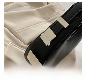 Close-up of polished gold-tone metal buckles on black leather shoulder bag detail