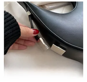 Detail of silver square buckle and fine stitching on a black leather shoulder bag
