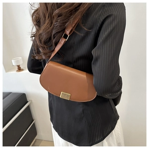 Macro shot of dark brown leather saddle bag with gold striped metal buckle and matte texture