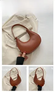 Detail view of the brown crescent bag showing the matte leather texture and metal buckle