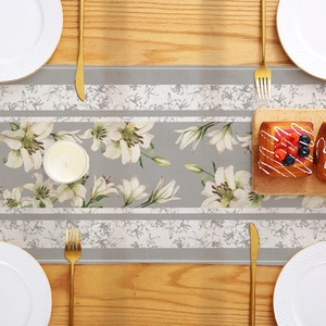 Grey table runner with lily flower print on a wooden dining table with elegant tableware