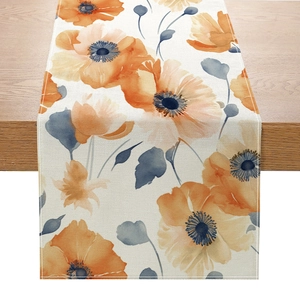 Polyester table runner with orange floral print on a light wood dining table surface