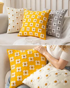 Gros plan de la broderie de marguerites touffetées sur une housse de coussin carrée
