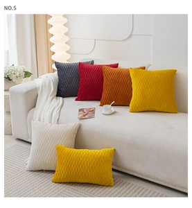 Detailed view of wavy pleated velvet pillow covers in multiple warm colors on a white sofa