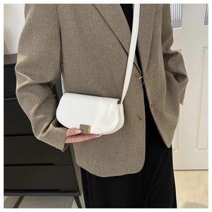 Close-up of white PU leather crossbody bag with elegant gold striped metal buckle detail