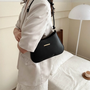 Minimalist black leather crescent shoulder bag with gold metal trim and knotted strap