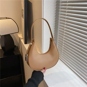 Minimalist camel leather crescent underarm bag with silver buckle in natural window light