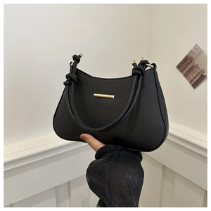 Detail showing the double-knotted handle and golden metal accents of the black handbag