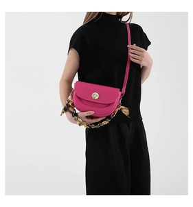 Rose pink saddle bag with silk scarf chain handle and gold clasp on a black outfit