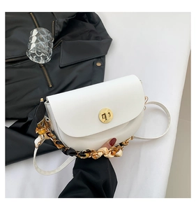 Detailed view of white saddle bag with golden lock, silk scarf chain, and smooth leather