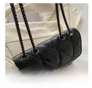 Detail shot of black quilted leather shoulder bag with metal eyelets and silver chain strap