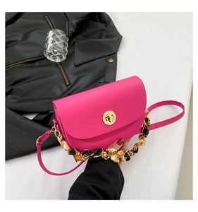 Detail of rose red faux leather saddle bag with silk scarf handle and gold twist lock