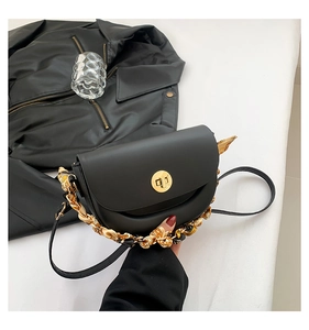 Detail of black leather saddle bag with gold clasp and decorative printed silk scarf chain